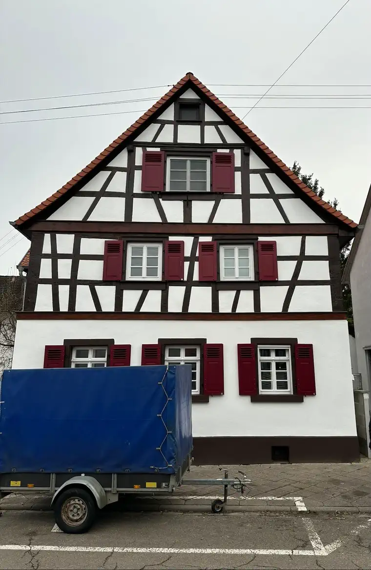 Saniertes Fachwerkhaus unter Denkmalschutz mit roten Klappläden, Giebelansicht