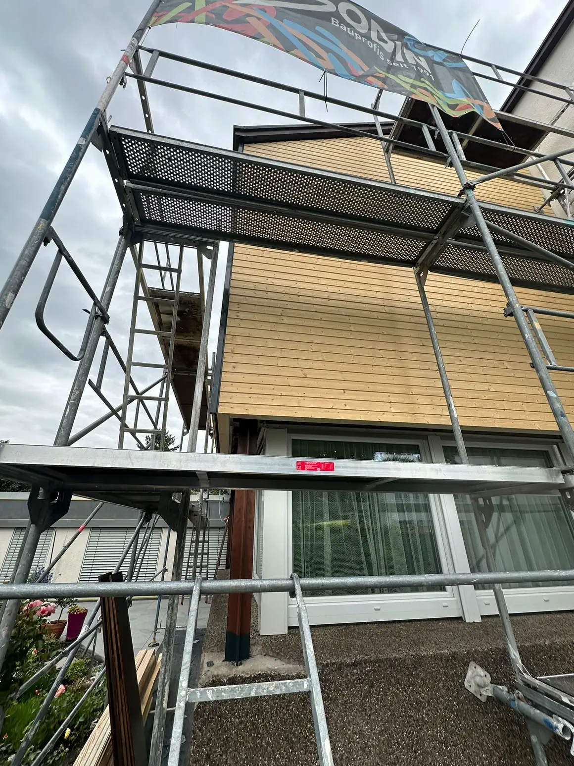 Gerüst mit Belägen und Seitenschutz vor der neuen Holzschalung