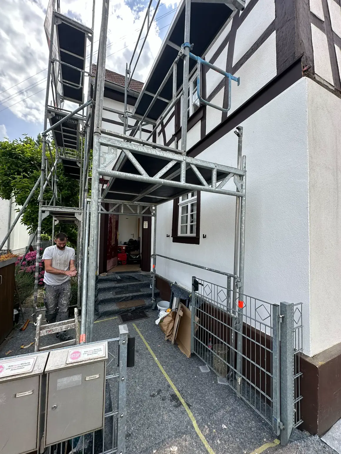 Gerüst über dem Hauseingang eines Riegelhauses, die Fassade ist frisch verputzt