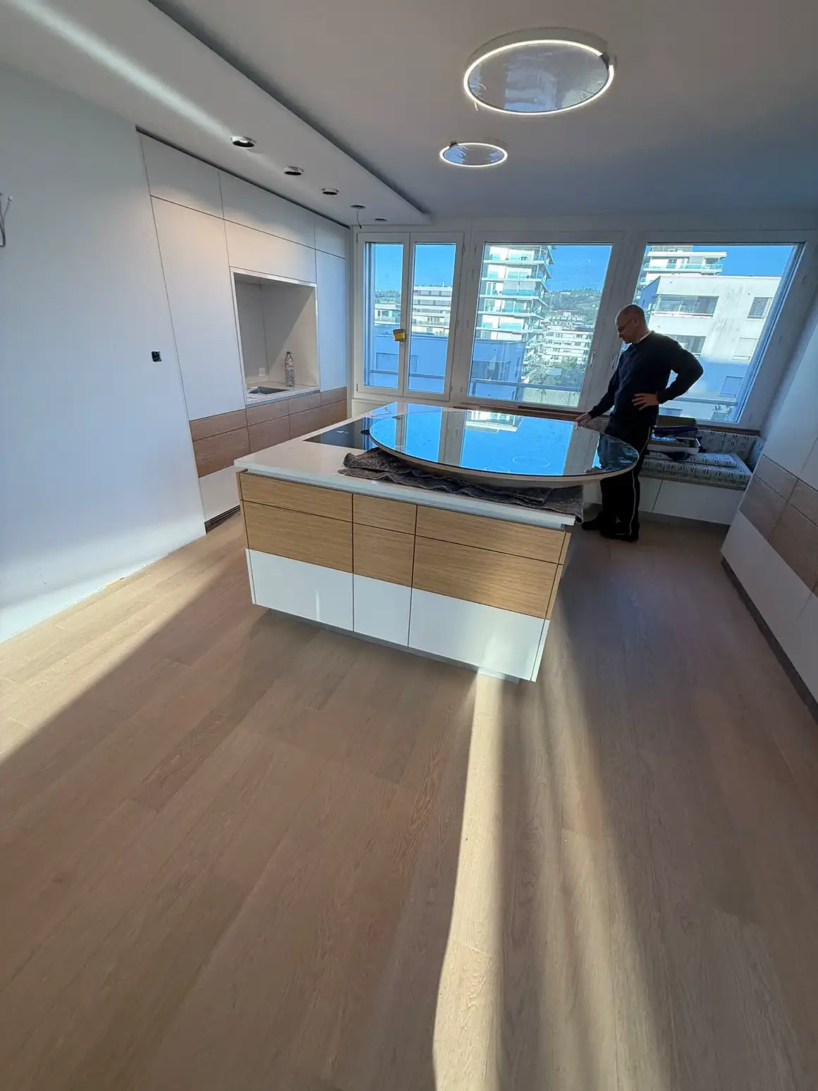 Küche mit freistehender Insel und Eichenfronten, dahinter die Fensterfront mit Sitzbank